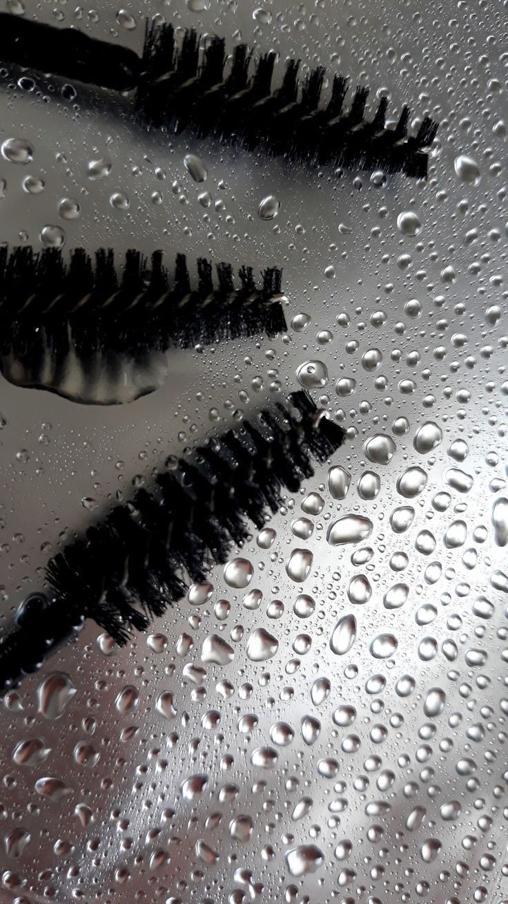 Brow lamination brushes on a wet, reflective surface.